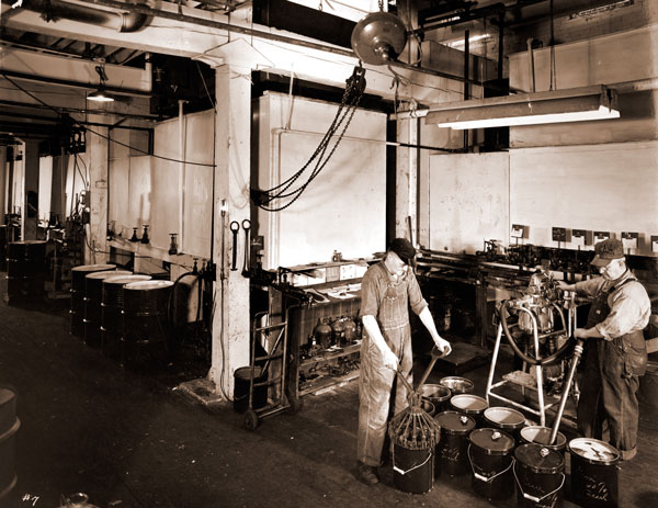 Two men working in a factory with several pails